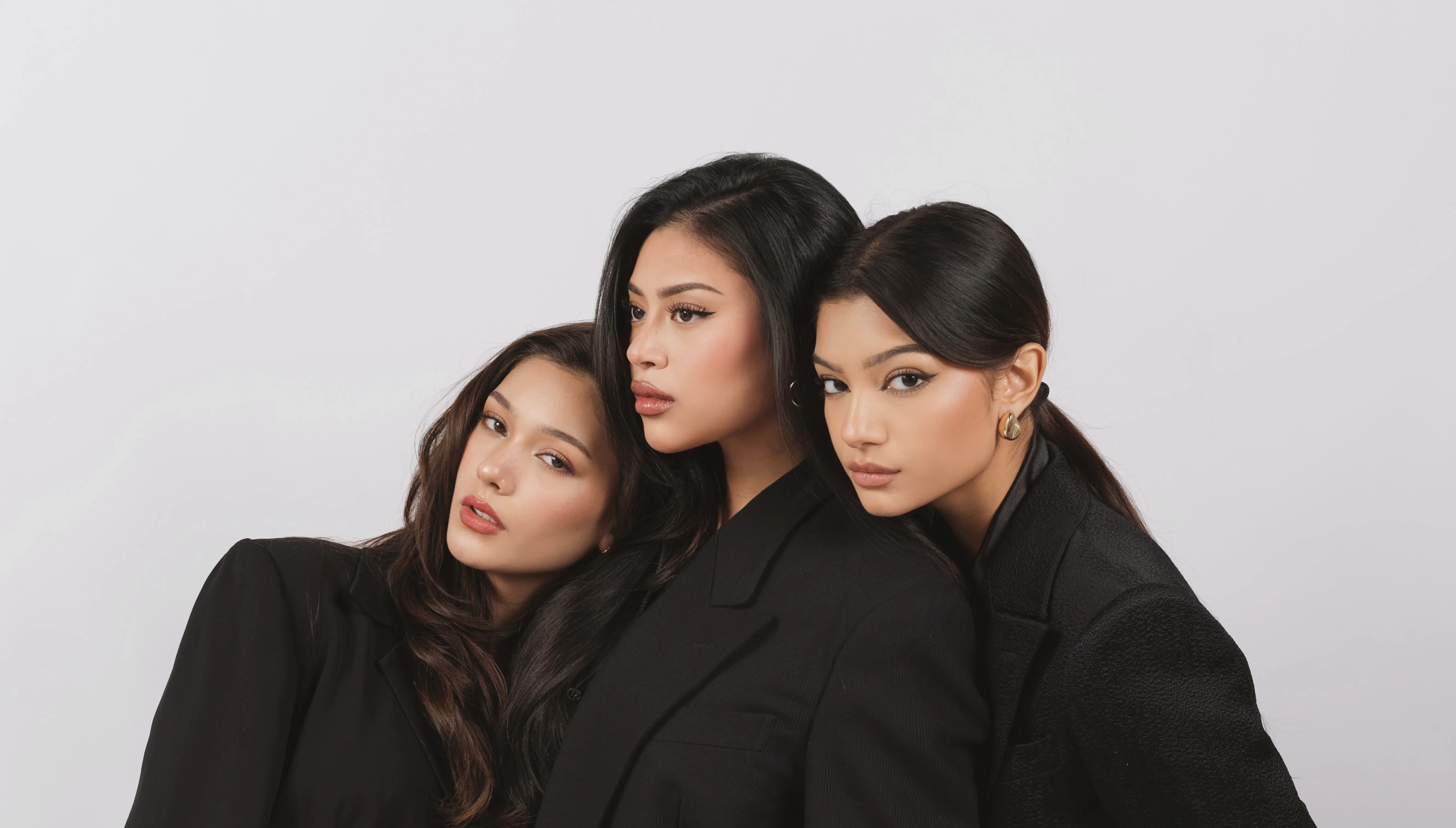 Three women with lifted lashes and soft brows, photographed in black blazers for MIRA Lash Studios